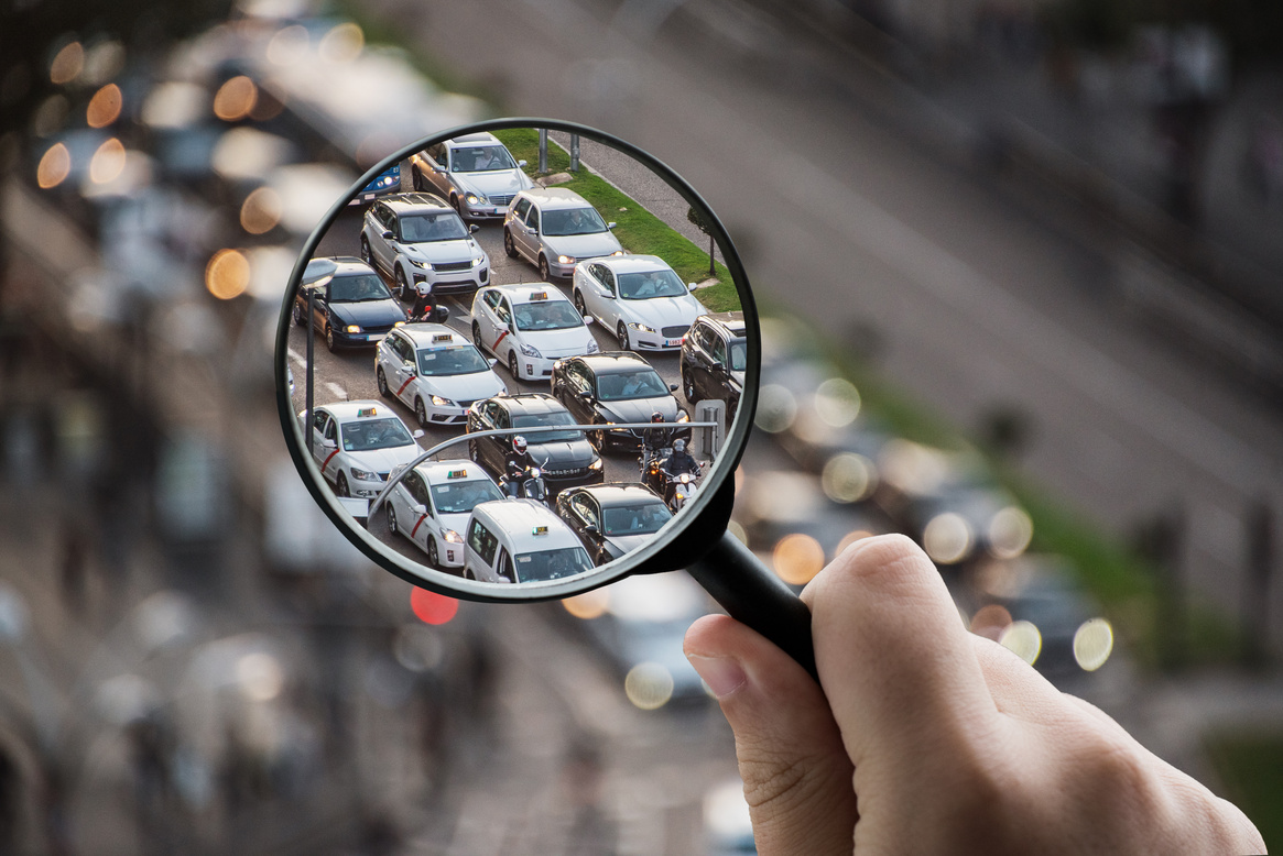 Magnifying glass focusing on traffic and urban mobility